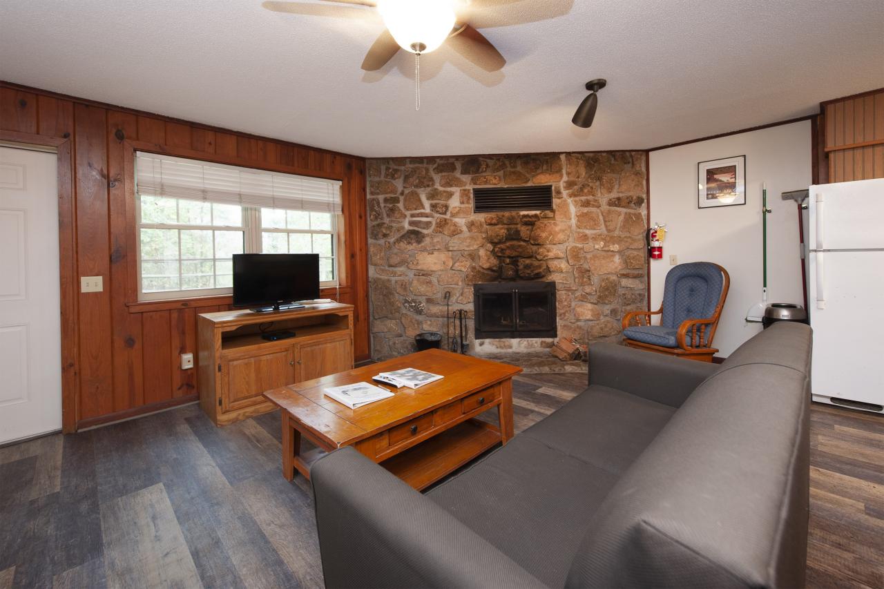 A view of the living room with seating area, tv and fireplace at Cabin 4 at Crowley's Ridge State Park